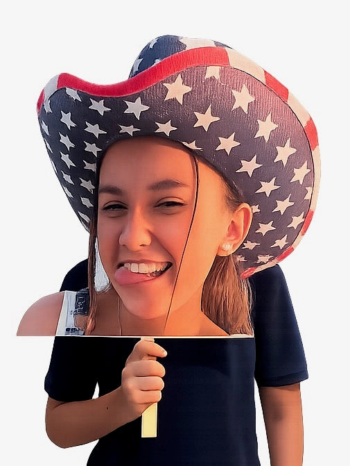 Handheld oversized photo cutout of a smiling face wearing a patriotic cowboy hat