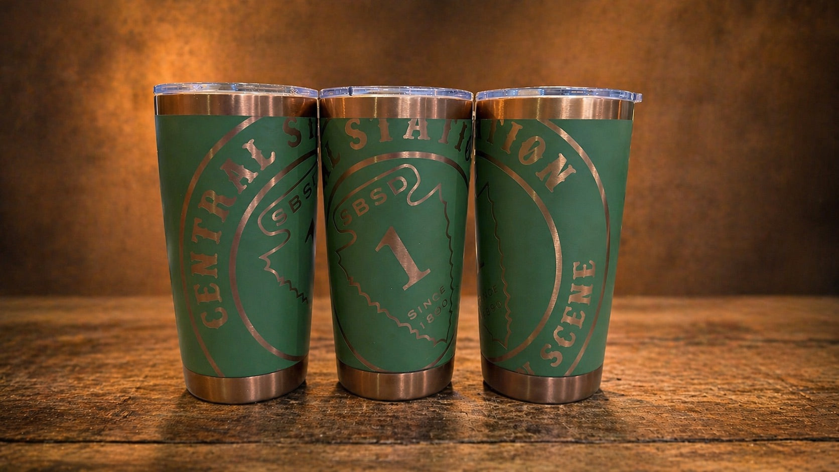 Three views of a green tumbler engraved with a Central Station sheriff department design